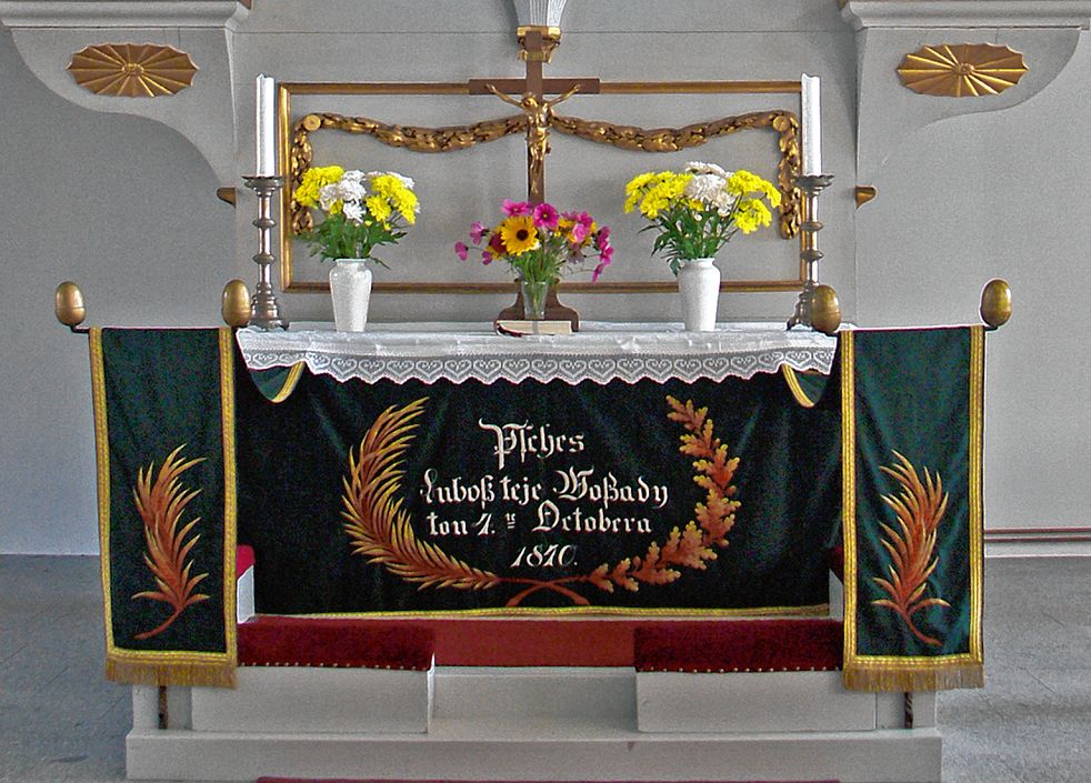 Wołtarna płachta z wěnowanjom »Psches / Lubosz teje Woßady / ton 4.te Octobera / 1840.«, darjena składnostnje zapokazanja fararja Hendricha Awgusta Krygarja, je dźensa po cyłej Łužicy najstarši parament ze serbskim napisom.  Foto: <b>zběrka Trudla Malinkowa</b>